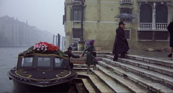 Movie still from “Don't Look Now” (1973), directed by Nicolas Roeg – A group of people walking down steps near a boat; Wide shot, High angle