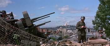 Movie still from “La Grande Vadrouille” (1966), directed by Gérard Oury – A man standing on top of a building next to a pile of rubble; Wide shot, Low angle