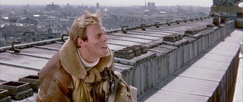 Movie still from “La Grande Vadrouille” (1966), directed by Gérard Oury – A man standing on top of a building with a city in the background; Close Up shot, Low angle