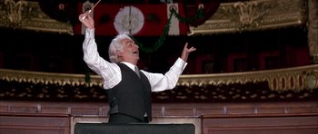 Movie still from “La Grande Vadrouille” (1966), directed by Gérard Oury – An older man in a black vest and a white shirt is holding his hands up in the air; Medium shot, Low angle