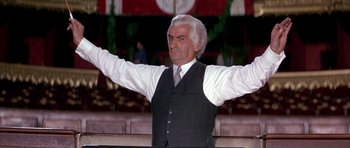 Movie still from “La Grande Vadrouille” (1966), directed by Gérard Oury – An older man in a vest and tie raising his arms; Medium shot, Low angle