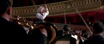 Movie still from “La Grande Vadrouille” (1966), directed by Gérard Oury – An older man is playing the violin in a orchestra; Medium shot, Low angle