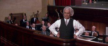 Movie still from “La Grande Vadrouille” (1966), directed by Gérard Oury – A man in a suit and tie standing in front of an audience; Medium shot, Low angle