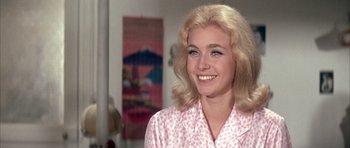 Movie still from “La Grande Vadrouille” (1966), directed by Gérard Oury – A woman with blonde hair wearing a pink and white shirt; Close Up shot, Over the shoulder angle