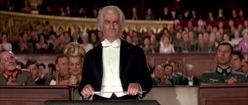 Movie still from “La Grande Vadrouille” (1966), directed by Gérard Oury – A man in a tuxedo is standing in front of an audience; Medium shot, Low angle