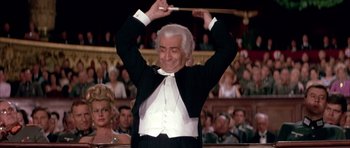 Movie still from “La Grande Vadrouille” (1966), directed by Gérard Oury – An older man in a tuxedo holding his hands in the air; Medium shot, Low angle