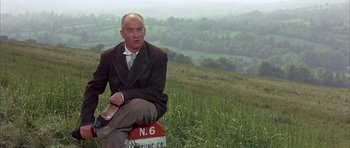 Movie still from “La Grande Vadrouille” (1966), directed by Gérard Oury – A man sitting on top of a hill in a field; Medium shot, Low angle
