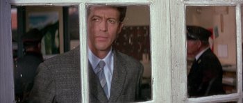 Movie still from “La Grande Vadrouille” (1966), directed by Gérard Oury – A man wearing a suit and tie looking out a window; Close Up shot, Over the shoulder angle