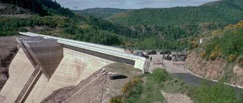 Movie still from “La Grande Vadrouille” (1966), directed by Gérard Oury – A view of a large dam with trees in the background; Extreme Wide shot, High angle