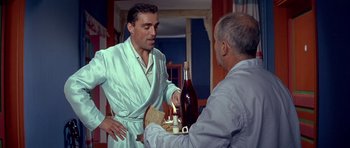 Movie still from “La Grande Vadrouille” (1966), directed by Gérard Oury – A man in a robe is handing a bottle to another man; Medium shot, Over the shoulder angle