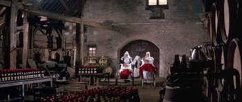 Movie still from “La Grande Vadrouille” (1966), directed by Gérard Oury – A group of women dressed in white and red are sitting in chairs in front of a brick wall; Wide shot, High angle