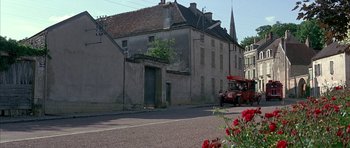 Movie still from “La Grande Vadrouille” (1966), directed by Gérard Oury – An old building with a bus parked on the side of the road; Extreme Wide shot, High angle