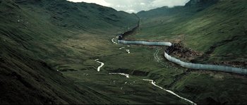 Movie still from “Doomsday” (2008), directed by Neil Marshall – An aerial view of a river running through a lush green field; Extreme Wide shot, High angle