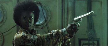 Movie still from “Doomsday” (2008), directed by Neil Marshall – A person holding a gun in a room; Medium shot, Low angle