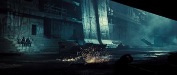 Movie still from “Doomsday” (2008), directed by Neil Marshall – A person is using a grinder to cut a metal object; Wide shot, Low angle