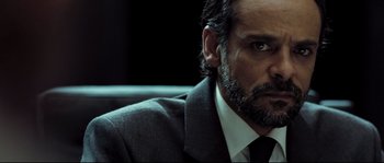 Movie still from “Doomsday” (2008), directed by Neil Marshall – A person wearing a suit and tie; Close Up shot, Over the shoulder angle