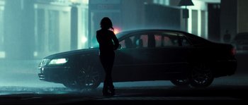 Movie still from “Doomsday” (2008), directed by Neil Marshall – A woman standing in front of a car on a city street; Wide shot, Low angle