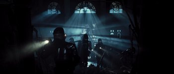 Movie still from “Doomsday” (2008), directed by Neil Marshall – A group of people standing in a dark room; Wide shot, Low angle