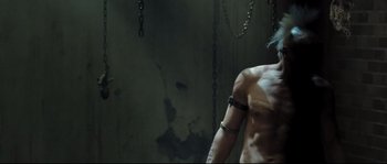 Movie still from “Doomsday” (2008), directed by Neil Marshall – A man with a tattoo on his arm is standing in chains; Medium shot, Low angle