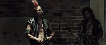 Movie still from “Doomsday” (2008), directed by Neil Marshall – A man in a leather jacket with a red mohawk; Medium shot, Low angle