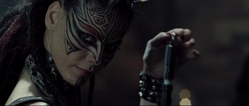 Movie still from “Doomsday” (2008), directed by Neil Marshall – A woman with a face paint on her face; Close Up shot, Over the shoulder angle