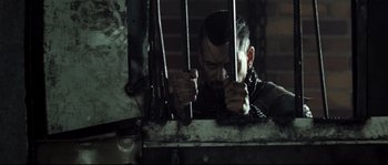 Movie still from “Doomsday” (2008), directed by Neil Marshall – A man in chains holding onto a metal bar; Close Up shot, Over the shoulder angle