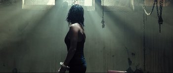 Movie still from “Doomsday” (2008), directed by Neil Marshall – A woman in a black shirt holding a white object; Medium shot, Low angle