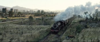 Movie still from “Doomsday” (2008), directed by Neil Marshall – A train traveling down train tracks next to a field; Extreme Wide shot, Low angle