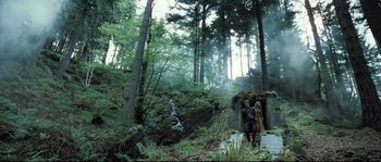 Movie still from “Doomsday” (2008), directed by Neil Marshall – Two people standing in the middle of a forest; Wide shot, Low angle