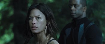 Movie still from “Doomsday” (2008), directed by Neil Marshall – A woman standing next to a man in the woods; Close Up shot, Over the shoulder angle