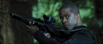 Movie still from “Doomsday” (2008), directed by Neil Marshall – A man holding a rifle in a forest; Close Up shot, Low angle