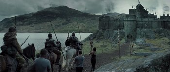 Movie still from “Doomsday” (2008), directed by Neil Marshall – A group of people on horseback near a castle; Extreme Wide shot, Low angle