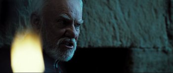 Movie still from “Doomsday” (2008), directed by Neil Marshall – An old man with a beard is looking at the camera; Close Up shot, Over the shoulder angle