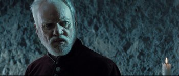 Movie still from “Doomsday” (2008), directed by Neil Marshall – An old man with a beard and a white mustache; Close Up shot, Low angle