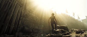 Movie still from “Doomsday” (2008), directed by Neil Marshall – A woman is walking through the sunlight on a rocky path; Wide shot, Low angle
