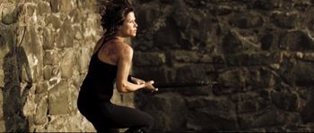 Movie still from “Doomsday” (2008), directed by Neil Marshall – A woman in a black top is jumping in the air; Medium shot, Low angle