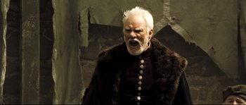 Movie still from “Doomsday” (2008), directed by Neil Marshall – An old man with white hair and a white beard; Medium shot, Low angle