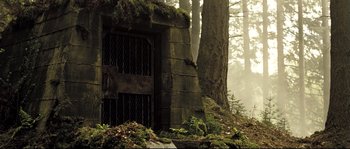 Movie still from “Doomsday” (2008), directed by Neil Marshall – A stone building in the middle of a forest; Wide shot, Low angle