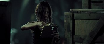Movie still from “Doomsday” (2008), directed by Neil Marshall – A woman holding a tablet in her hands; Medium shot, Low angle