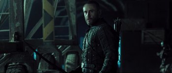 Movie still from “Doomsday” (2008), directed by Neil Marshall – A person holding a bow and arrow; Medium shot, Low angle