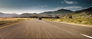 Movie still from “Doomsday” (2008), directed by Neil Marshall – A car driving down the middle of a road; Extreme Wide shot, Low angle