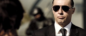 Movie still from “Doomsday” (2008), directed by Neil Marshall – A person wearing a suit and sunglasses; Close Up shot, Low angle