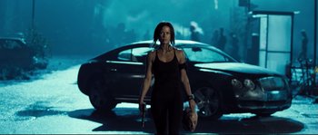 Movie still from “Doomsday” (2008), directed by Neil Marshall – A woman holding a gun while standing in front of a car; Medium shot, Low angle