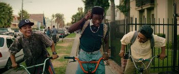 Movie still from “Dope” (2015), directed by Rick Famuyiwa – A young man with headphones is riding a bike; Medium shot, Over the shoulder angle