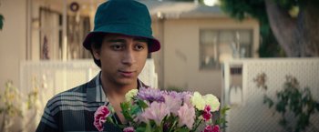 Movie still from “Dope” (2015), directed by Rick Famuyiwa – A young man holding a bouquet of flowers; Close Up shot, Over the shoulder angle