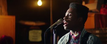 Movie still from “Dope” (2015), directed by Rick Famuyiwa – A man is singing into a microphone in front of a microphone stand; Close Up shot, Low angle