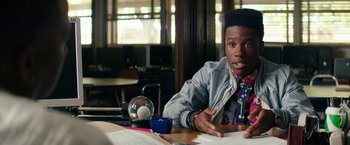 Movie still from “Dope” (2015), directed by Rick Famuyiwa – A young man sitting at a table in front of papers; Close Up shot, Over the shoulder angle