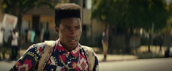 A young man with a very large afro is looking into the camera