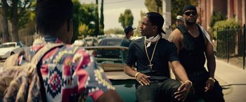 Movie still from “Dope” (2015), directed by Rick Famuyiwa – A man sitting on the back of a boat in the water; Medium shot, Over the shoulder angle