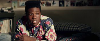Movie still from “Dope” (2015), directed by Rick Famuyiwa – A man in a colorful shirt is laying on a bed; Close Up shot, Overhead angle